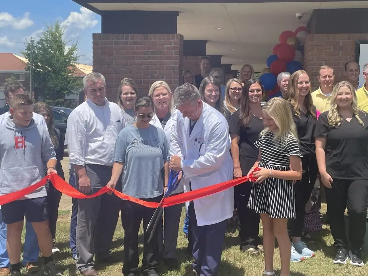 NMVC Ribbon cutting ceremony outside. doctor is using large scissors to cut the ribbon